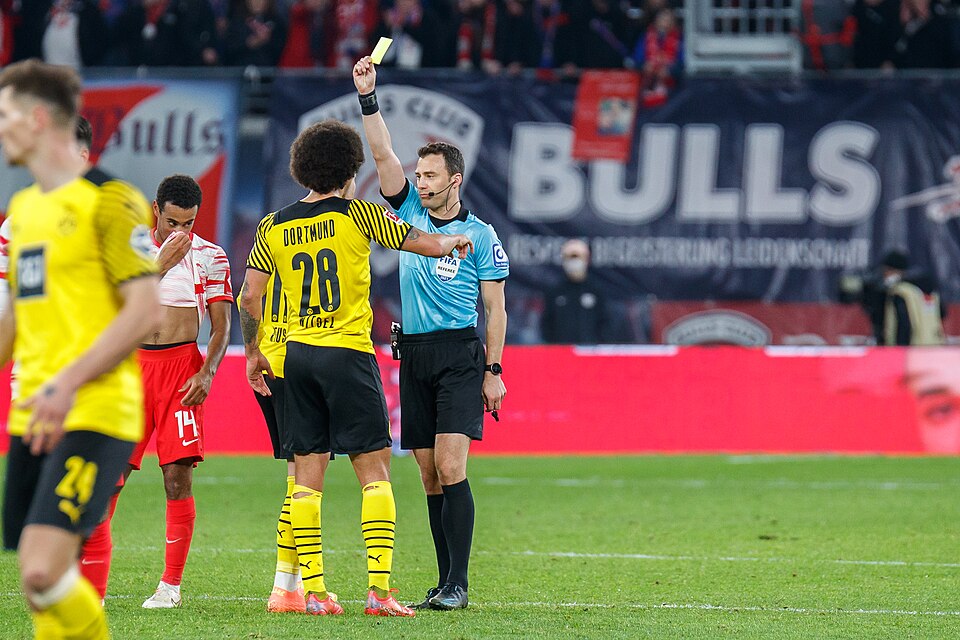 Árbitro muestra tarjeta amarilla en un partido de fútbol profesional
